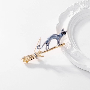 Détail d'une broche chat sur balai volant en émail bleu et strass scintillants