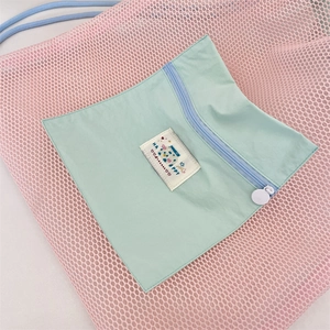 Détail d'un sac à dos en maille rose avec poche zippée bleu clair et étiquette Happy tissée