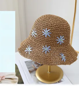 Detailed view of handmade woven straw hat with blue daisy and golden display stand