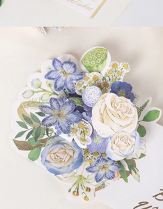 Detail of 3D pop-up flower bouquet on greeting card with blue petals and gold foil