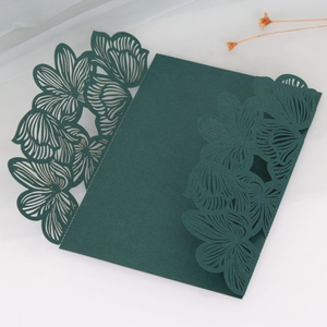 Dark green laser cut floral wedding invitation card on white background with dried flowers