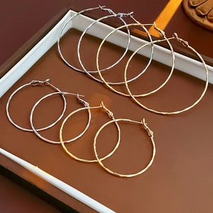 Macro shot of gold and silver hoop earrings with hammered texture in a jewelry display box
