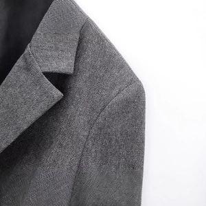 Close-up of grey herringbone wool blend blazer showing premium fabric texture and collar detail