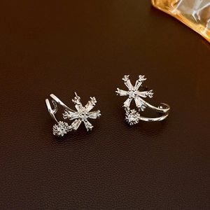 Macro shot of silver snowflake earrings with sparkling cubic zirconia on brown leather surface