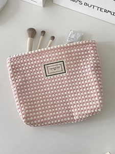 Detail of pink and white checkered puff texture makeup bag with Pleasant Time label