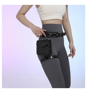 Détail du sac de jambe en similicuir noir avec texture crocodile et boucles en métal