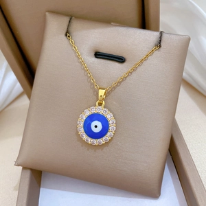 Close-up of golden Evil Eye pendant with blue center and crystal halo on silk
