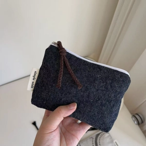 Macro shot of dark denim mini pouch featuring simple wish label and braided zipper pull