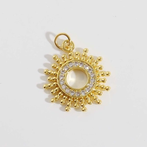 Détail d'un pendentif soleil doré serti de zircons blancs sur fond blanc épuré