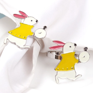 Detail of bunny napkin rings with white enamel rabbit holding a pocket watch on metal band
