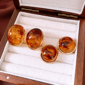Close-up of caramel round earrings with tortoiseshell texture and gold-plated edges