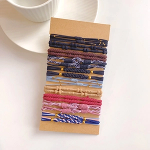 Detail of multi-color woven hair tie set on kraft card with gold bead accents