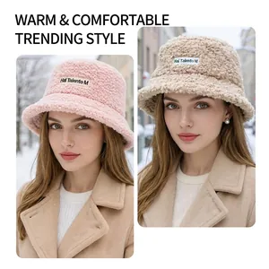 Winter faux shearling bucket hats for women in pink and beige with logo label