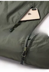 Detailansicht der olivgrünen Outdoorjacke mit Reißverschlusstasche und Handy-Größenvergleich