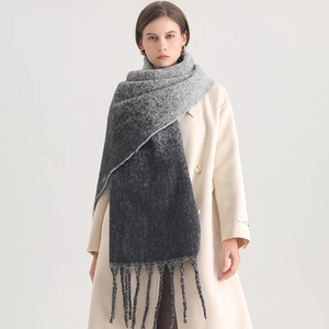 Detail showing the gray gradient knitted scarf texture and fringe decorative edge