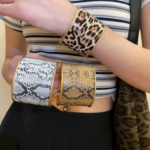 Detail showing wide cuff bracelets with leopard and snake skin textures in gold finish
