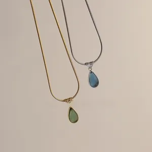 Detail of gold and silver snake chains with green and blue teardrop opal pendants