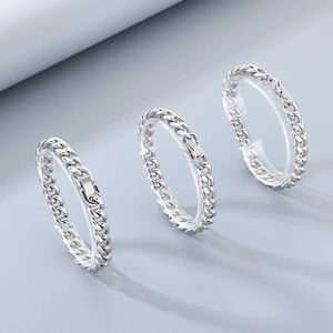 Trois bracelets gourmettes en acier inoxydable argenté sur un fond bleu clair