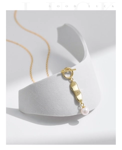 Detail of s925 silver pearl necklace featuring a gold T-bar clasp and fluid metal pendant