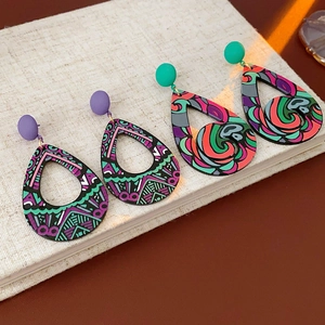 Détail de boucles d'oreilles géométriques en forme de goutte sur fond de lin au soleil