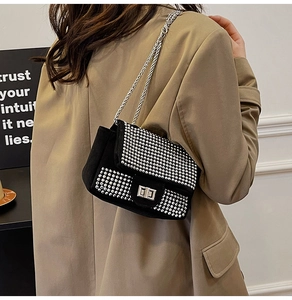 Detail of a black suede crossbody bag with sparkling rhinestones and silver chain strap