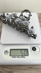 Vue détaillée d'une pince à cheveux camélia de 50g sur une balance électronique de mesure