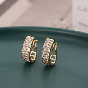 U-shaped gold-toned earrings with micro-set zircon rows on a matte tray