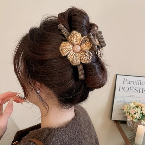Detail of knitted flower hair claw with pearl on brunette hair in French vintage style