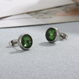 Détail macro de boucles d'oreilles en acier titane argenté avec pierres vertes