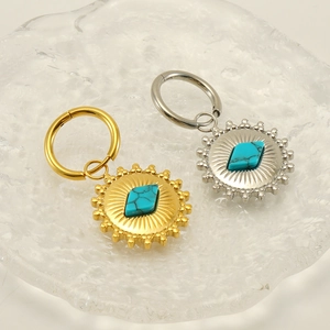Dettaglio di orecchini boho a raggiera con pietre turchesi in finitura oro e argento
