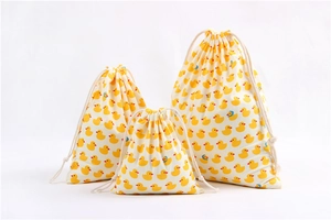 Three-piece set of cream fabric drawstring bags with yellow duck prints in varied sizes