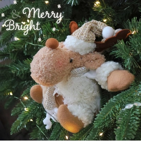Plush reindeer Christmas ornament with warm festive lighting and Merry & Bright text
