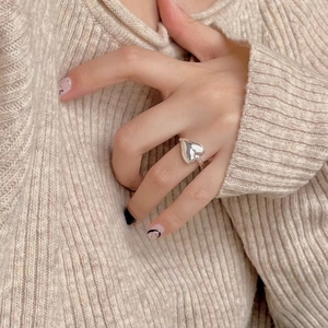 Polished 925 sterling silver heart ring worn on hand with a cozy beige knit sweater