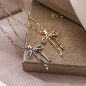 Elegant gold and silver bow pendant necklace with zircon crystals and asymmetrical tassels