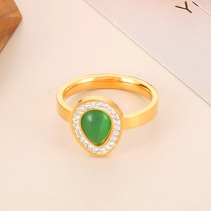 Detailed close-up of golden ring featuring green teardrop stone and white crystal halo