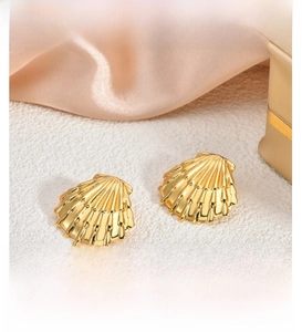 Close-up of 18K gold-plated shell earrings with detailed radial metal texture
