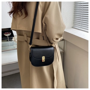 Side view of black faux leather saddle bag with gold metal buckle on a model