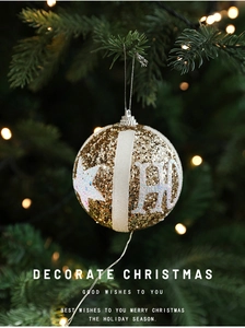 Close-up of golden glitter Christmas ornament with white star and H-letter detail