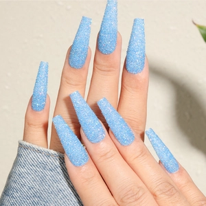 Close-up of long square blue glitter press-on nails worn on hands with sparkling finish