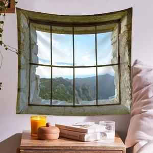 Detail of mountain landscape wall tapestry hanging over a bed with warm candlelight decor