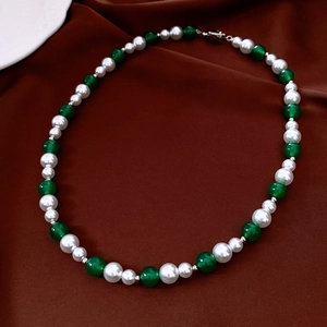 Detail of vintage necklace with white pearls, green beads, and silver lobster clasp