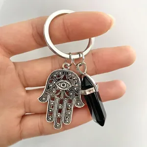 Macro detail of Hamsa Hand and black hexagonal crystal pillar on a silver keychain