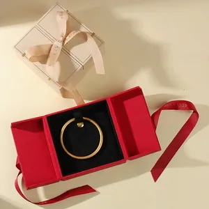 Elegant red three-fold jewelry gift box with ribbon and gold ring on black velvet base
