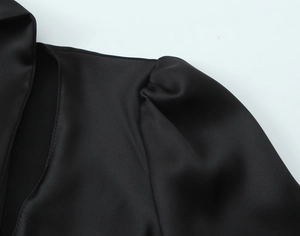 Macro view of black satin fabric showing the puffed shoulder detail and silk-like texture