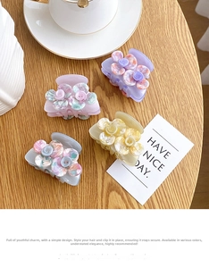 Close-up of four floral acetate hair claws in pastel colors on a rustic wooden table