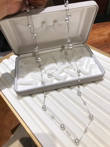 Detail of elegant silver chain necklace with multiple white pearls on a velvet jewelry box