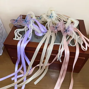 Dettaglio di fermagli per capelli a farfalla con perle e lunghi nastri di seta colorati