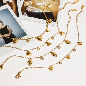 Flat lay of 18K gold plated stainless steel heart and zircon bracelets with photos