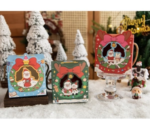 Three-color Christmas gift boxes with Santa illustrations set on festive artificial snow