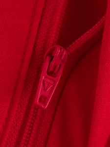 Gros plan d'une fermeture éclair rouge sur un gilet avec détail de logo géométrique